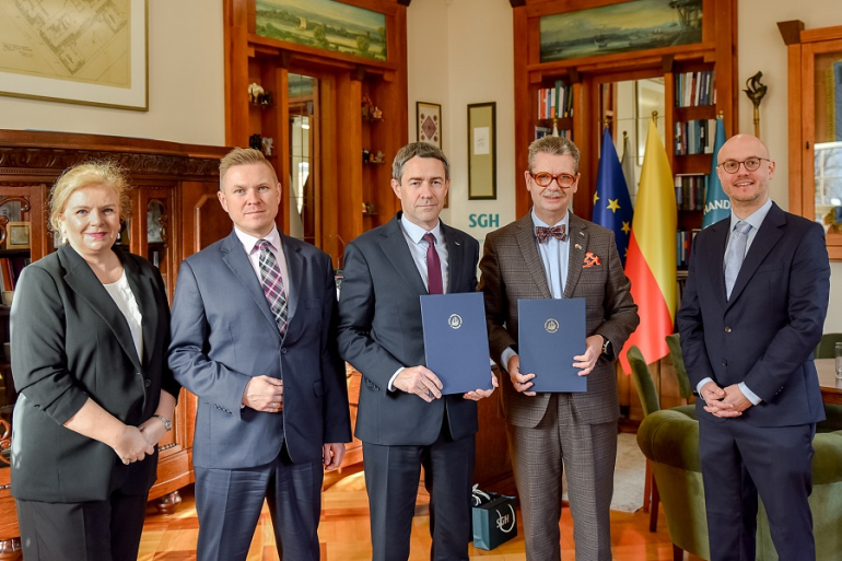 czterech mężczyzn i kobieta stoją po podpisaniu porozumienia; dwóch mężczyzn trzyma w rękach teczki z dokumentami