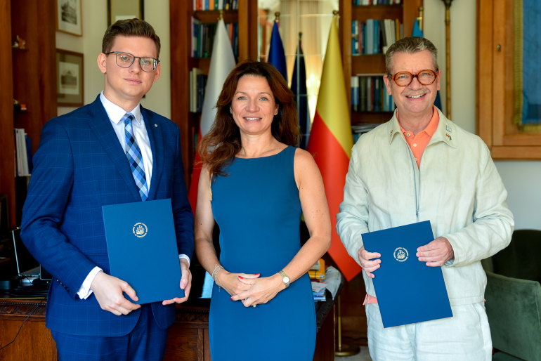 dwóch mężczyzn i kobieta po podpisaniu porozumienia pozują do zdjęcia w gabinecie