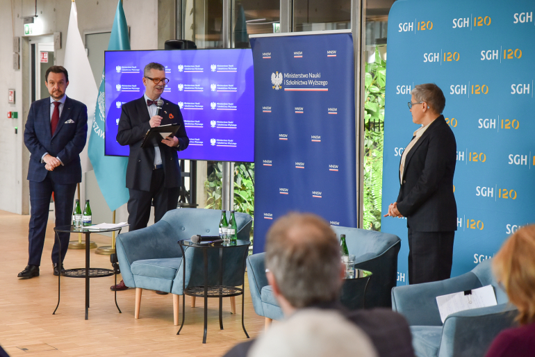 dwóch mężczyzn i i kobieta stoją na tle ścianek z logami