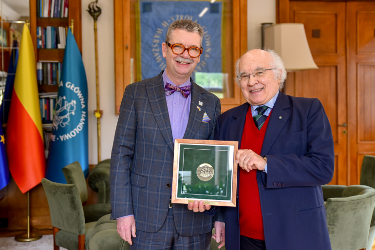 dwóch mężczyzn w gabinecie pokazuje medal za zasługi 