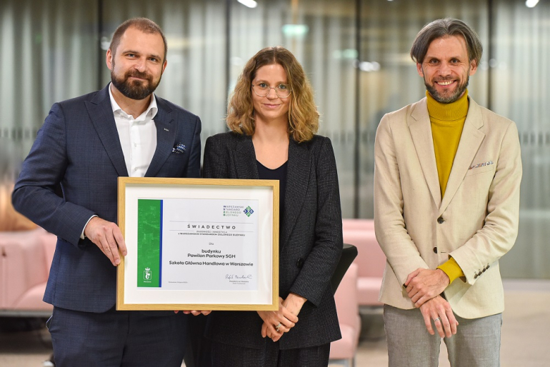 Na zdjęciu trzy osoby trzymające obraz