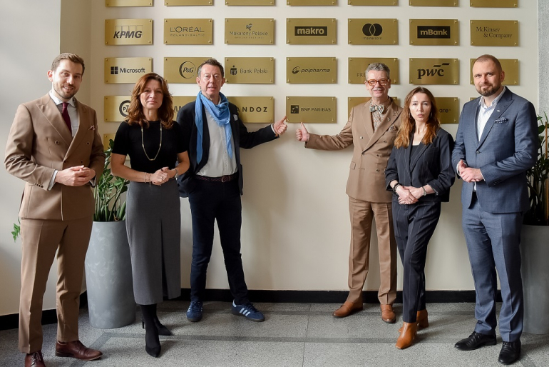 na zdjęciu kilkoro osób pod tablica Klubu artnerów