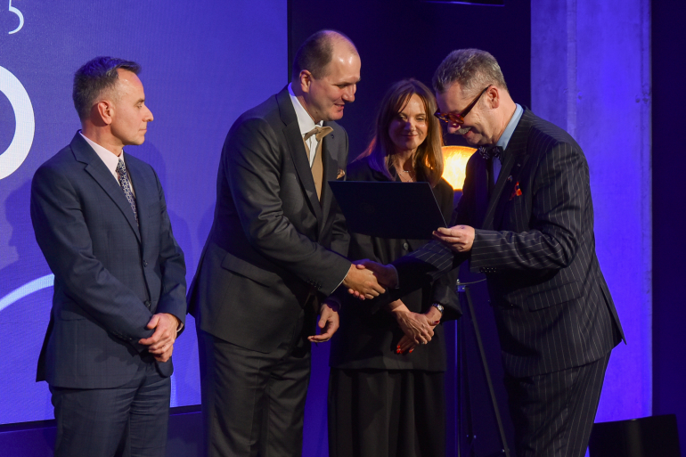 mężczyzna wręcza nagrodę drugiemu mężczyźnie - voucher na studia podyplomowe