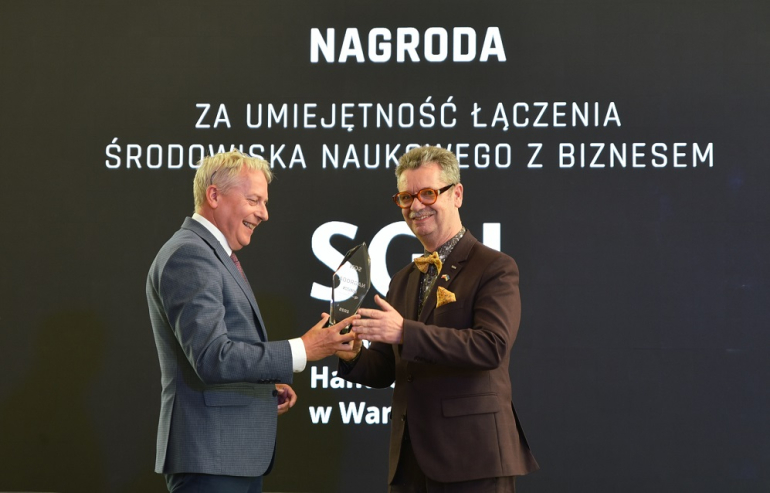 jeden mężczyzna przekazuje drugiemu statuetkę na gali