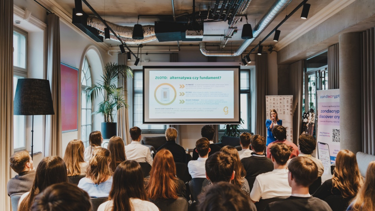 zdjęcie zrobione z tyłu sali przedstawiające studentów słuchających panelu