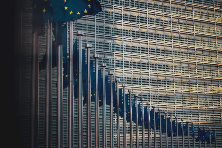 flagi unijne na tle budynku KE w Brukseli