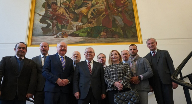 zdjęcie zbiorowe kilku osób na klatce schodowej, z tyłu obraz na ścianie