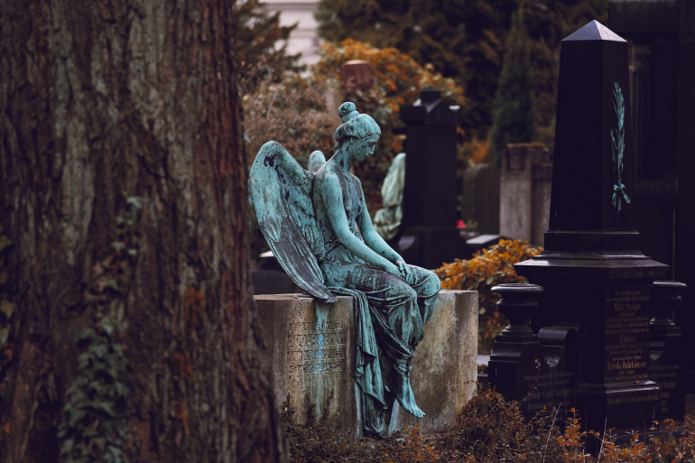Zdjęcie kolorowe. Rzeźba anioła na tle cmentarza